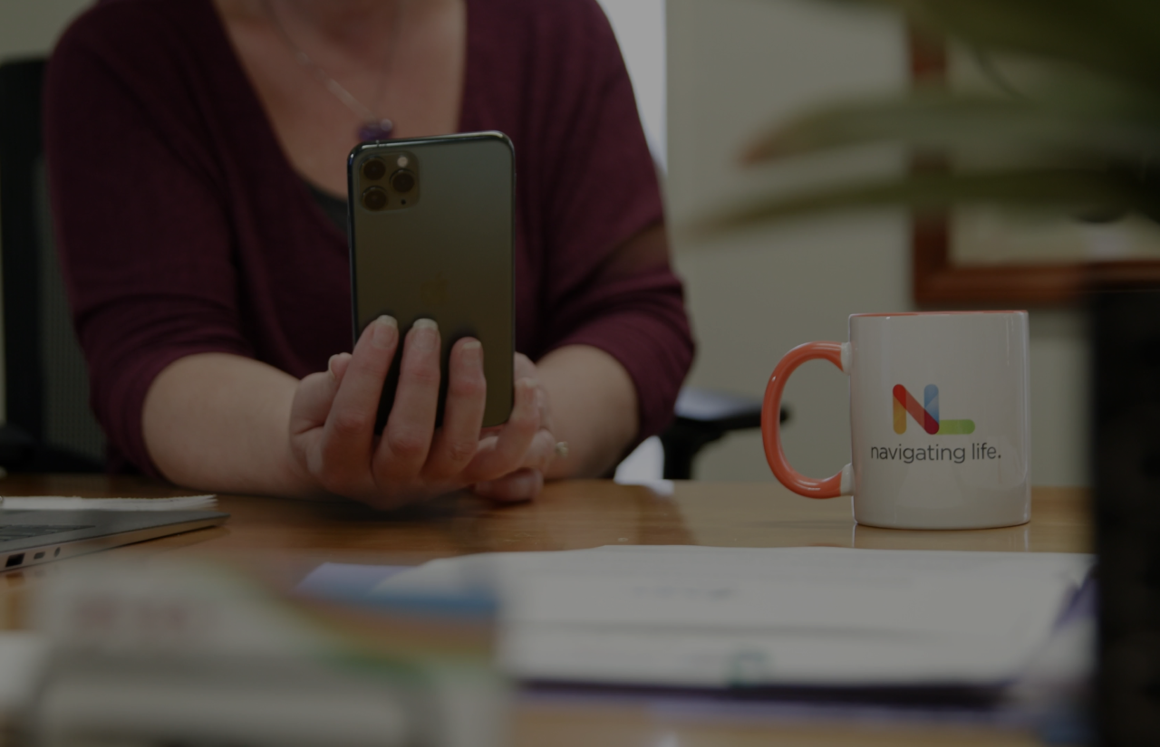 Woman holding a phone with a Navigating Life mug